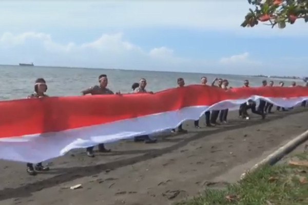 Gaungkan Nasionalisme, Polantas Bitung Bentangkan Bendera Merah Putih di Bibir Pantai